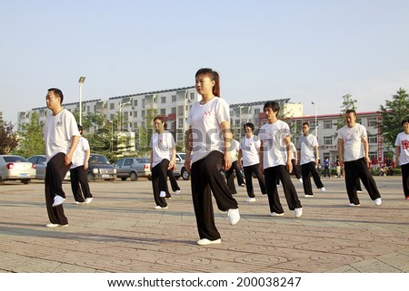 LUANNAN COUNTY - JUNE 14: A group of people were performing Tai chi chuan on the gym in the square, on june 14, 2014, LuanNan county, hebei province, China