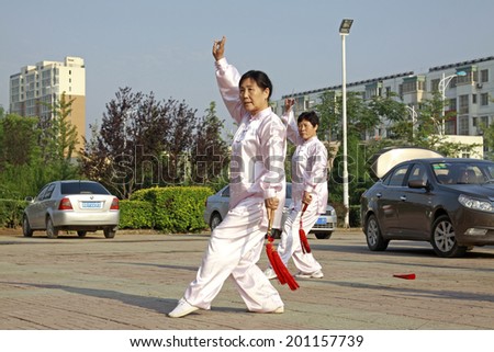 LUANNAN COUNTY - JUNE 14: An old lady was performing Taiji sword on the gym in the square, on june 14, 2014, LuanNan county, hebei province, China