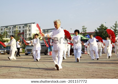 LUANNAN COUNTY - JUNE 14: A group of old people were performing Tai chi chuan on the gym in the square, on june 14, 2014, LuanNan county, hebei province, China
