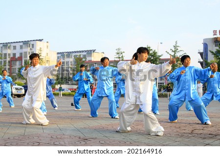 LUANNAN COUNTY - JUNE 14: A group of people were performing Tai chi chuan on the gym in the square, on june 14, 2014, LuanNan county, hebei province, China