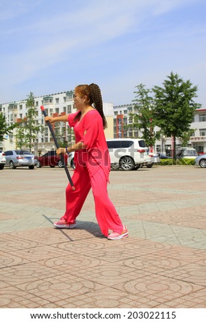 LUANNAN COUNTY - JUNE 29: woman in red was performing stick fencing in the square, on june 29, 2014, LuanNan county, hebei province, China