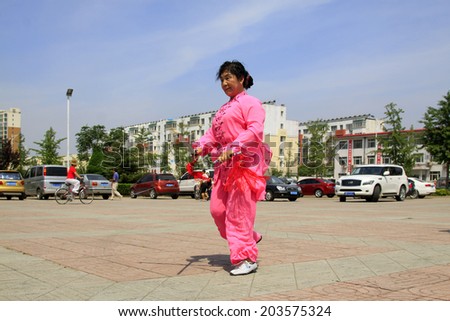 LUANNAN COUNTY - JUNE 29: woman in red was performing fencing in the square, on june 29, 2014, LuanNan county, hebei province, China