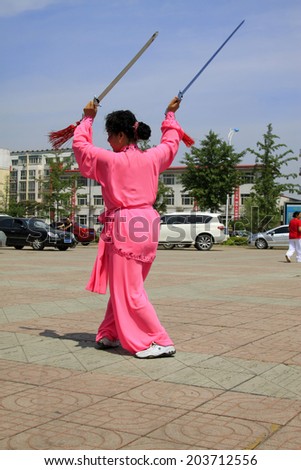 LUANNAN COUNTY - JUNE 29: woman in red performing fencing in the square, on june 29, 2014, LuanNan county, hebei province, China