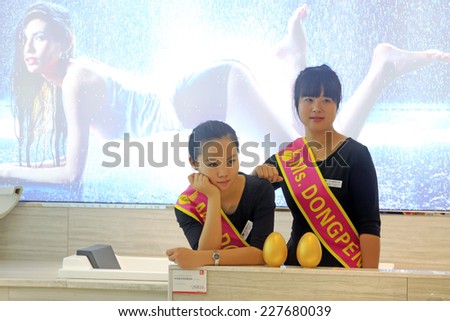 TANGSHAN CITY - SEPTEMBER 13: Female store staff introducing products to customers in front of the huge advertising, on september 13, 2014, Tangshan City, Hebei Province, China