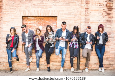 Friends group using smartphone against wall at university college backyard break - Young people addicted by mobile smart phone - Technology concept with always connected millennials - Filter image