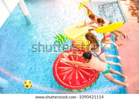Top view of active friends jumping at swimming pool party - Vacation concept with happy guys and girls having fun in summer day at luxury resort - Dynamic young people on warm bright sunshine filter