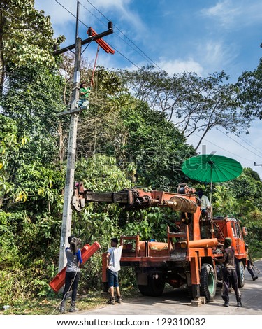 KO LANTA, THAILAND - FEBRUARY 22: manual workmen fix an electric pole on February 22, 2013 in Ko Lanta, Thailand. As often happens, they find themselves in very dangerous security conditions.
