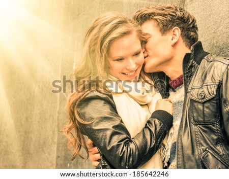 Young happy couple in love at the beginning of a Love Story - Fashion man whispers a soft kiss in the ear of the loved young woman.