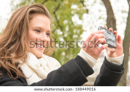 Beautiful happy young woman taking a selfie with a modern cell phone in the park - Lifestyle of a single blonde girl smiling on a smartphone outdoors