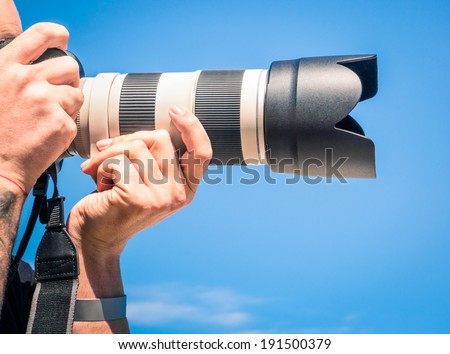 Photographer outdoors with big zoom digital lens as professional equipment getting ready to shoot a photo Photographer outdoors with big zoom digital lens as professional equipment getting ready to shoot a photo