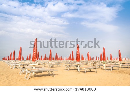 Red umbrellas and sunbeds at Rimini Beach - Italian summer overview at the beginning of the season