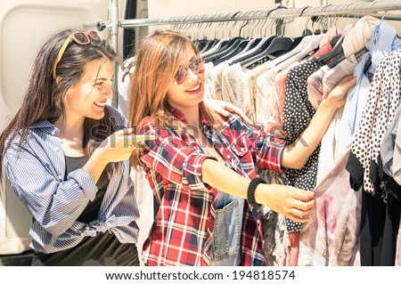 Young beautiful women at the weekly cloth market - Best friends sharing free time having fun and shopping in the old town in a sunny day