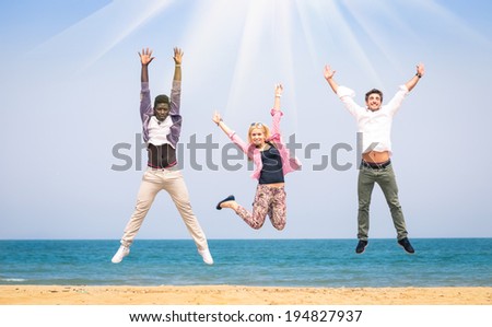 Three multiracial friends jumping at the beach - Concept of happiness and friendship against racism