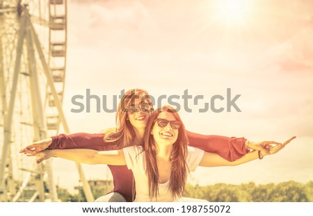 Best friends enjoying time together outdoors at ferris wheel - Concept of freedom and happiness with two girlfriends having fun - Vintage filtered look