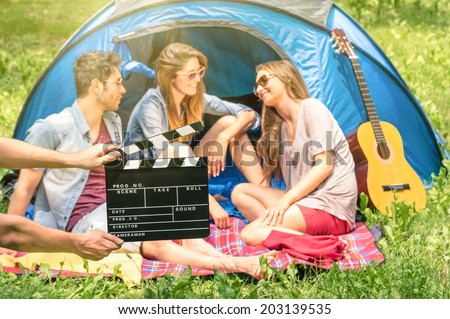 Group of friends camping in the park - clapperboard with young actors in the nature - Concept of youth and friendship with vintage scenario