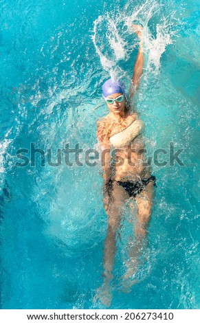 Beautiful young woman swimming in backstroke style - Concept of sport and fun in swimming pool