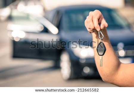 Man\'s hand holding modern car keys ready for rental - Concept of transportation with automobile second hand sale and trade