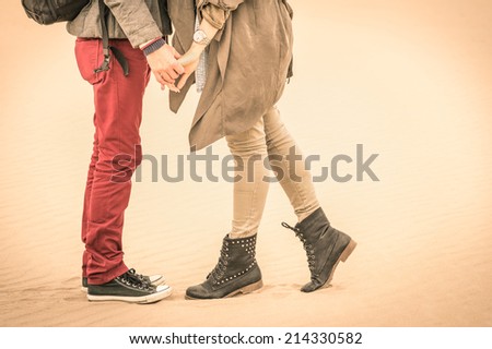 Concept of love in autumn - Couple of young lovers kissing outdoors with closeup on legs and shoes - Desaturated nostalgic filtered look