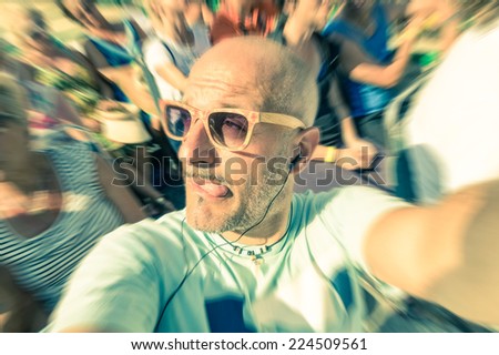 Bald funny man taking a selfie in the crowd with stupid tongue out expression - Travel lifestyle enjoying moment of carefree loneliness - Vintage filtered look