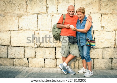 Happy senior couple having fun with a modern smartphone - Concept of active elderly and interaction with new technologies - Travel lifestyle without age limitation