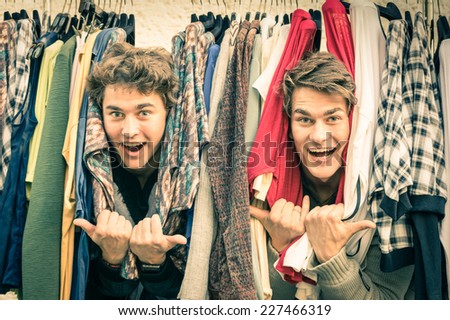Young hipster brothers at the weekly cloth market - Best friends sharing free time having fun and shopping in the old town in a sunny day - Guys enjoying everyday life moments