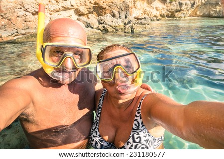 Senior happy couple taking a selfie at Blue Lagoon in Gozo and Comino - Travel to mediterranean island of Malta - Concept of active elderly and fun around the world experimenting new technologies