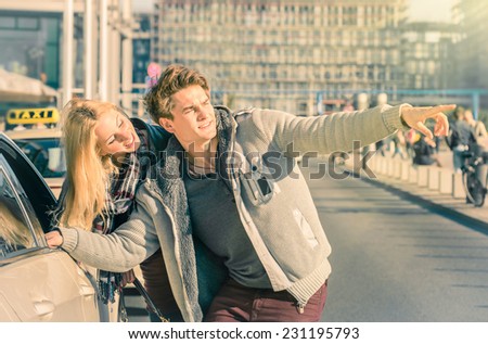 Young couple of lovers dealing with a taxi cab in the city center - Handsome man and beautiful woman explaining street directions to taxicab - Sunny day of a love story on a warm vintage filtered look