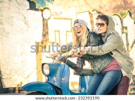 Young couple of lovers haviing fun on a vintage scooter moped - Handsome man in playful attitude with his beautiful girlfriend - Beginning of a love story on a warm sunny winter day