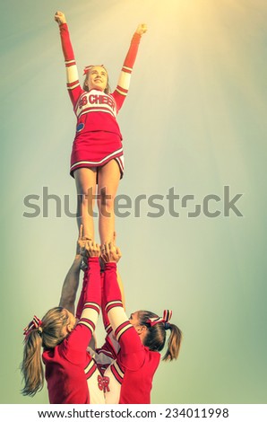 Cheerleaders in action on a vintage filtered look - Concept of unity and team sport - Training at college high school with young female teenagers
