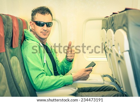 Young hipster man passenger satisfied with thumbs up after boarding - Concept of low coast flight and connection with modern technologies on board - Alternative lifestyle traveling around the world