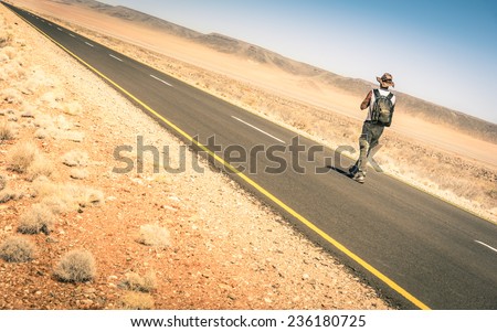 Lonely man walking along the road among the namibian african desert - Concept of alternative lifestyle - Travel trip adventure around the world