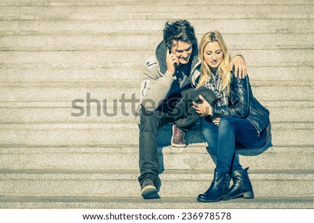 Beautiful hipster couple in love having a smartphone call - Modern concept of connection in a relationship together with mobile phone technology - City stairs urban lifestyle and everyday life rapport