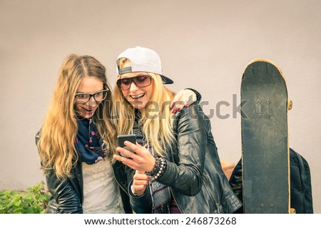 Best friends enjoying time together outdoors with smartphone - Concept of new trends and technology with hipster girlfriends having fun in urban city area - Alternative four seasons fashion clothes
