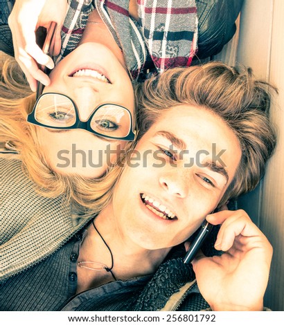 Couple in love having fun with smartphones - Top view of happy hipster lovers - Youth concept with new trends and technologies - Warm saturated vintage filtered look inspiring the upcoming spring