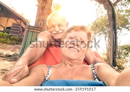 Senior happy couple taking selfie in Thailand trip - Adventure concept of active elderly and fun around the world  - Warm filtered look with genuine tilted horizon and soft focus due to backlighting