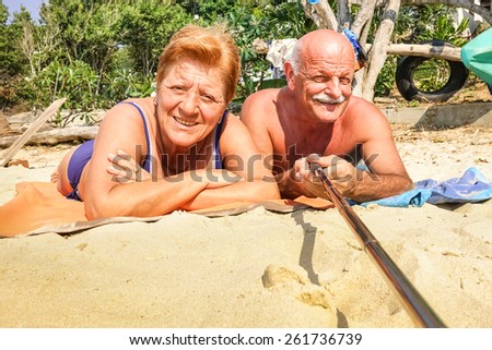 Senior happy couple taking selfie with stick in Thailand trip - Adventure concept of active elderly and fun around the world - Hot sunny day with real saturated light conditions