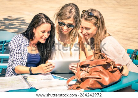 Young hipster girlfriends studying and having fun together with tablet - Social interaction on new technology trends and internet connection in everyday vintage lifestyle - Sunny day warm lighting