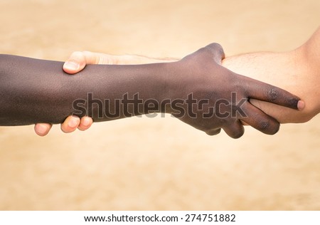 Black and white hands in modern handshake to show each other friendship and respect - Helping and respecting each other against racism - Slightly crispy detailed filtered look on defocused background