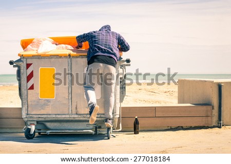 Young tramp rummaging in trash container looking for food and reusable goods - Modern concept of poverty with normal citizens becoming suddenly poor - Economy crisis and people with living issues