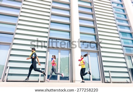 Group of young people running in modern urban area - Fitness girls running with male trainer coach in the city - Sport concept with friends jogging in business center downtown in a sunny bright day