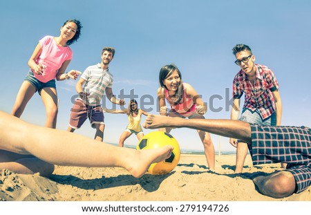 Group of multiracial friends playing beach soccer at beginning of summer - Concept of multi cultural friendship fun and sport against racism - Vintage filter with main focus on girl near the ball