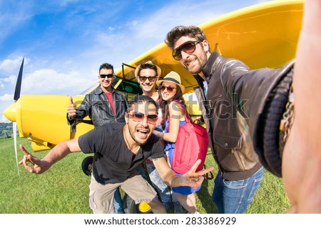 Best friends taking selfie at aeroclub with ultra light airplane - Happy friendship fun concept with young people and new technology trend - Sunny afternoon vivid color tones - Fisheye lens distortion