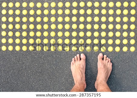 Naked human barefoot on asphalt road at tactile bumps paving - Life concept of human feeling with bare feet of blind people on the floor sidewalk warning pad - Social welfare assistance and facilities