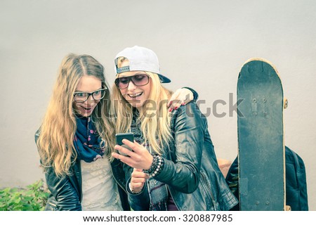 Female best friends enjoying time with smartphone - New trends and technology with hipster girlfriends having fun together - Soft focus on girl with baseball cap - Retro nostalgic filtered look