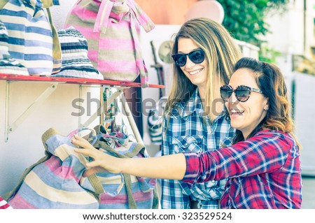 Young beautiful women girlfriends at flea market looking for bags - Best friends sharing free time having fun and shopping during travel - Soft vintage marsala filtered look - Focus on smallest girl