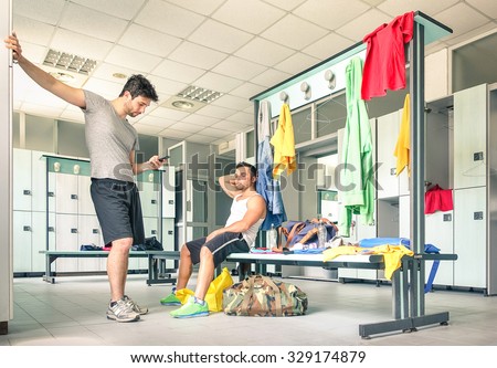 Young people at gym dressing room - Handsome guys at fitness studio doing their own staff before training - Social concept with lack of communication - Man looking at smartphone not talking to friends
