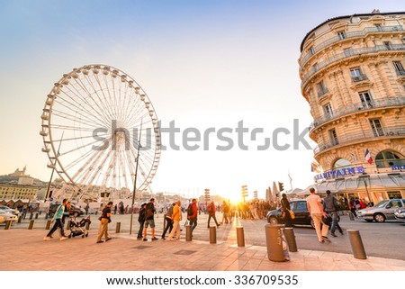 MARSEILLE, FRANCE - NOVEMBER 7, 2015: everyday life with local people and tourists at old sea port during sunset - Ferris wheel at the docks near the famous street \