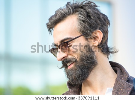 Portrait of hipster guy with confident face expression - Autumn fashion male model posing outdoors - Young man with beard and alternative mustache - Soft retro filter and shallow depth of field