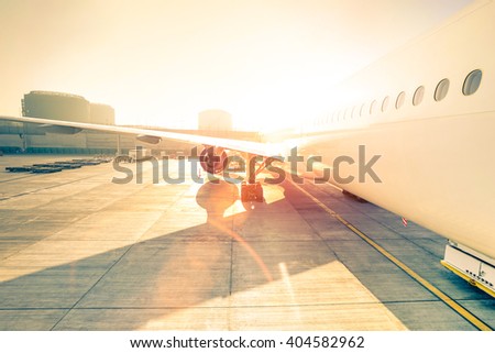 Airplane at terminal gate ready for takeoff - Modern international airport at sunset - Travel concept around the world - Wide angle distortion with rose quartz filter and enhanced sunshine lens flare