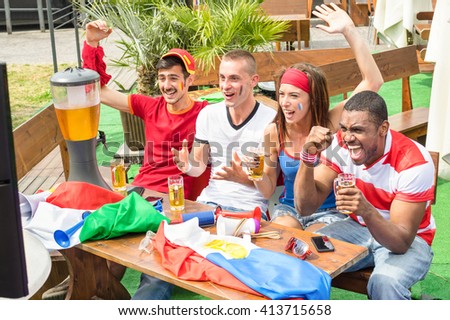 Young football supporter fans cheering with beer watching soccer match - Friends people with multicolored soccer tshirts and flags having fun - Sport championship concept - Warm afternoon color tones